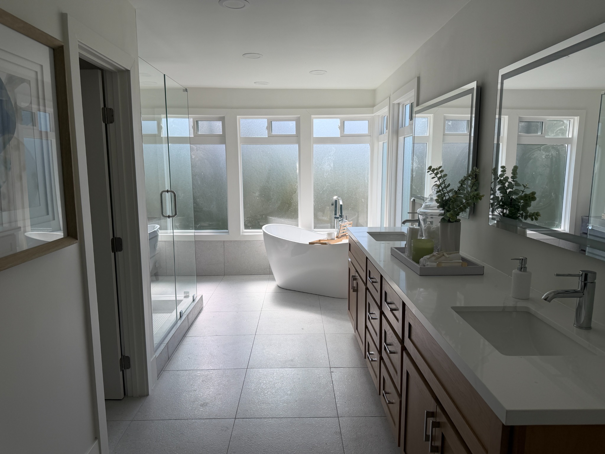 Renovated bathroom with freestanding tub, glass shower, and dual vanity